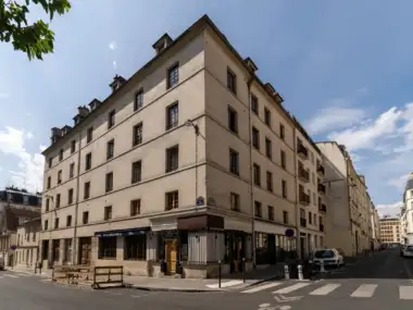 Vue d un immeuble d angle haussmannien à Paris sous un ciel bleu dégagé.