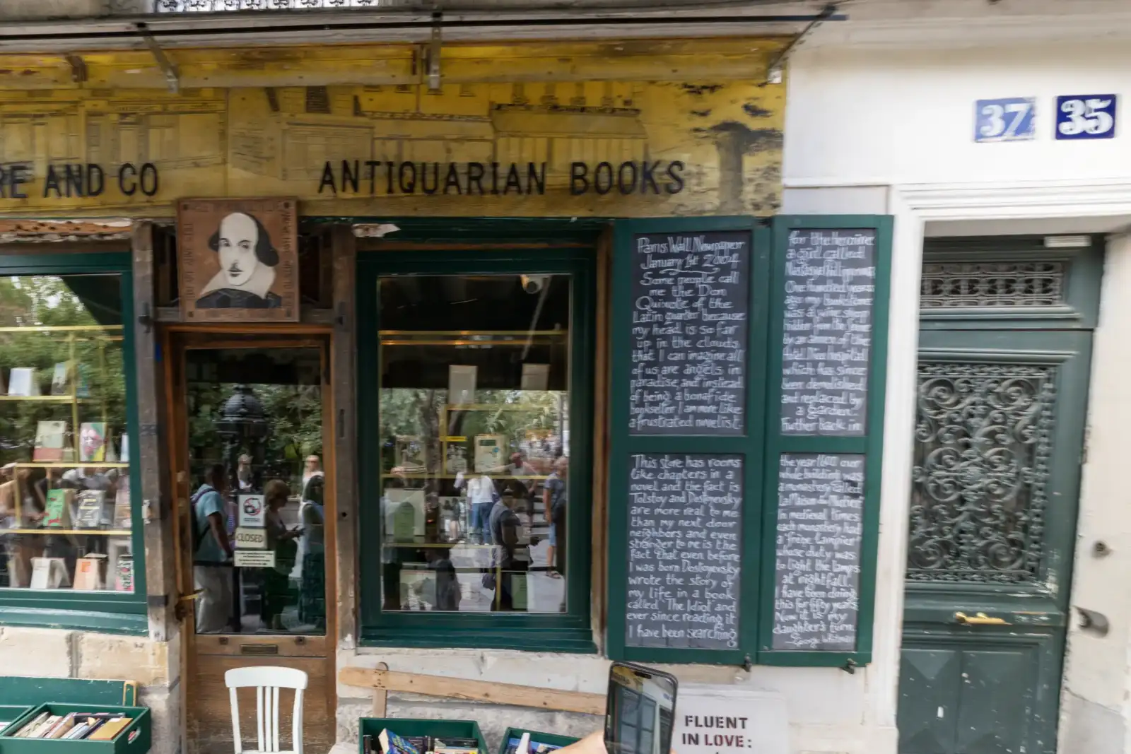 Façade de la célèbre librairie Shakespeare and Company à Paris, avec panneaux manuscrits.
