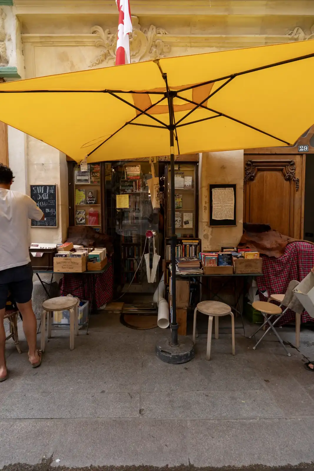 Devant l'Abbey Bookshop à Paris, un grand parasol jaune abrite des livres et des étals.