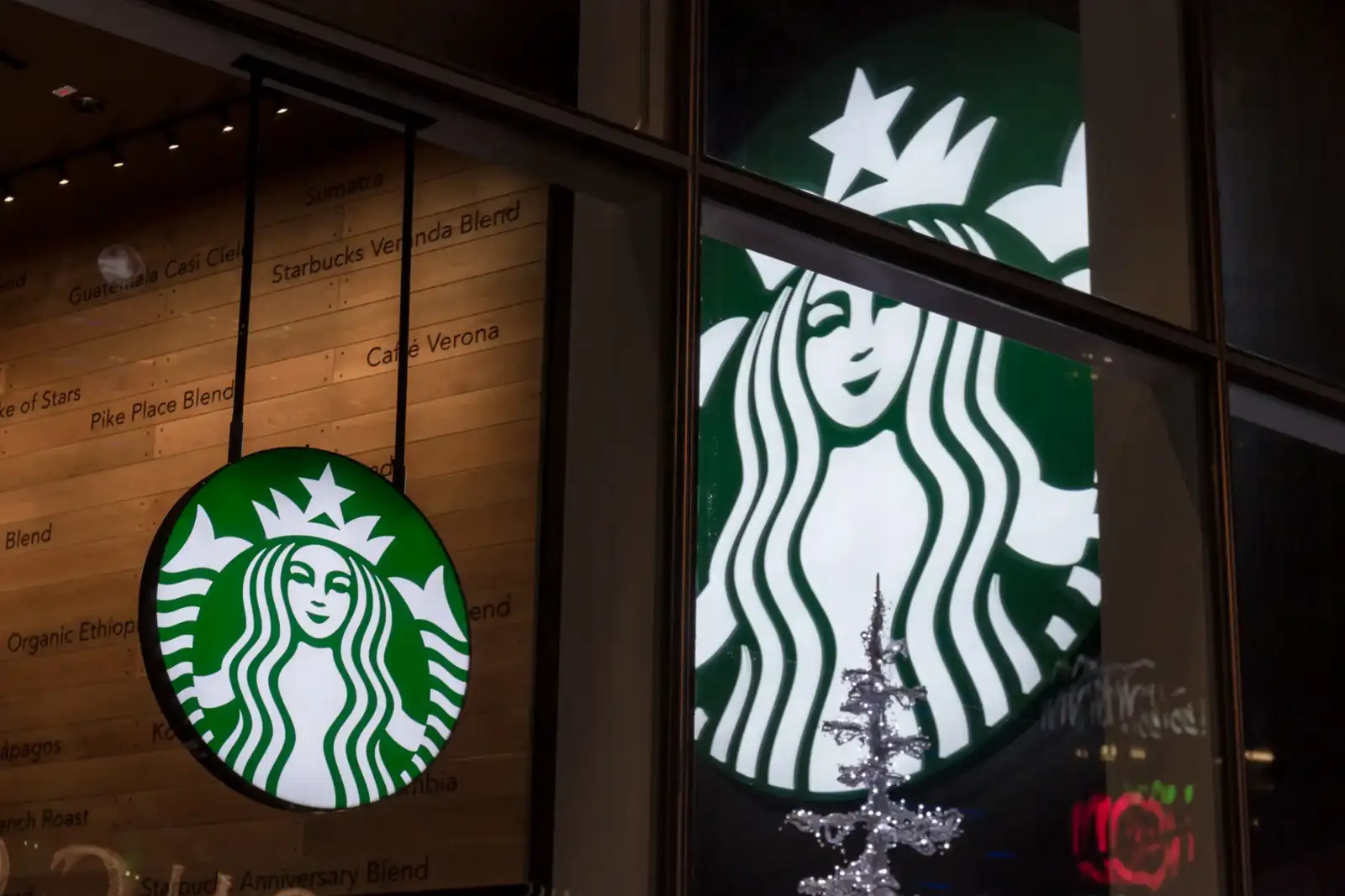 Un logo Starbucks lumineux vert et blanc est visible sur la vitrine du magasin parisien.