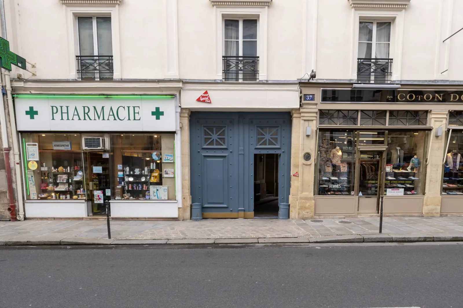La façade du MAIF Social Club entre une pharmacie et une boutique à Paris.