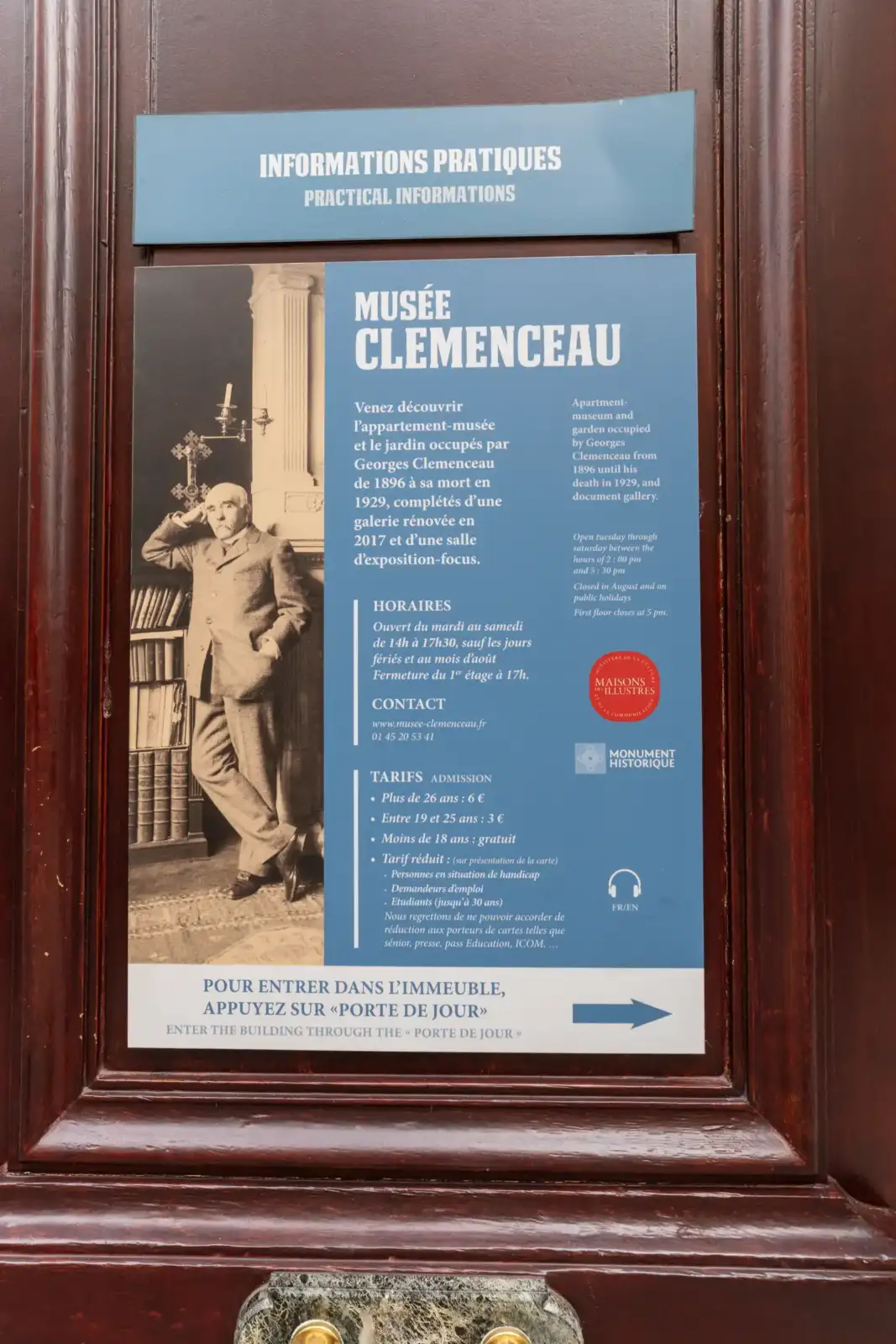 Panneau d information bleu sur une porte en bois du musée Clemenceau à Paris.