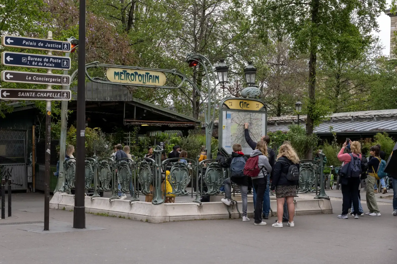 Des touristes consultent une carte devant l'entrée Art nouveau du métro Cité à Paris.