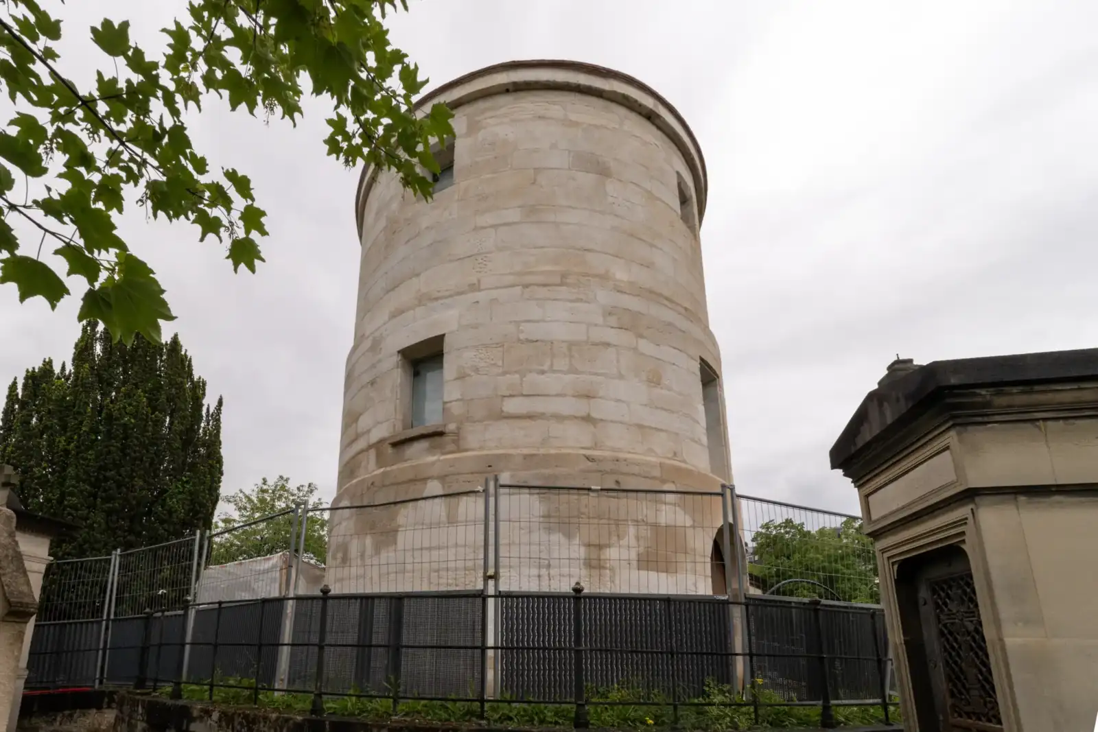 Vue en contre-plongée de l'ancien moulin de la Charité entouré de grilles à Paris.