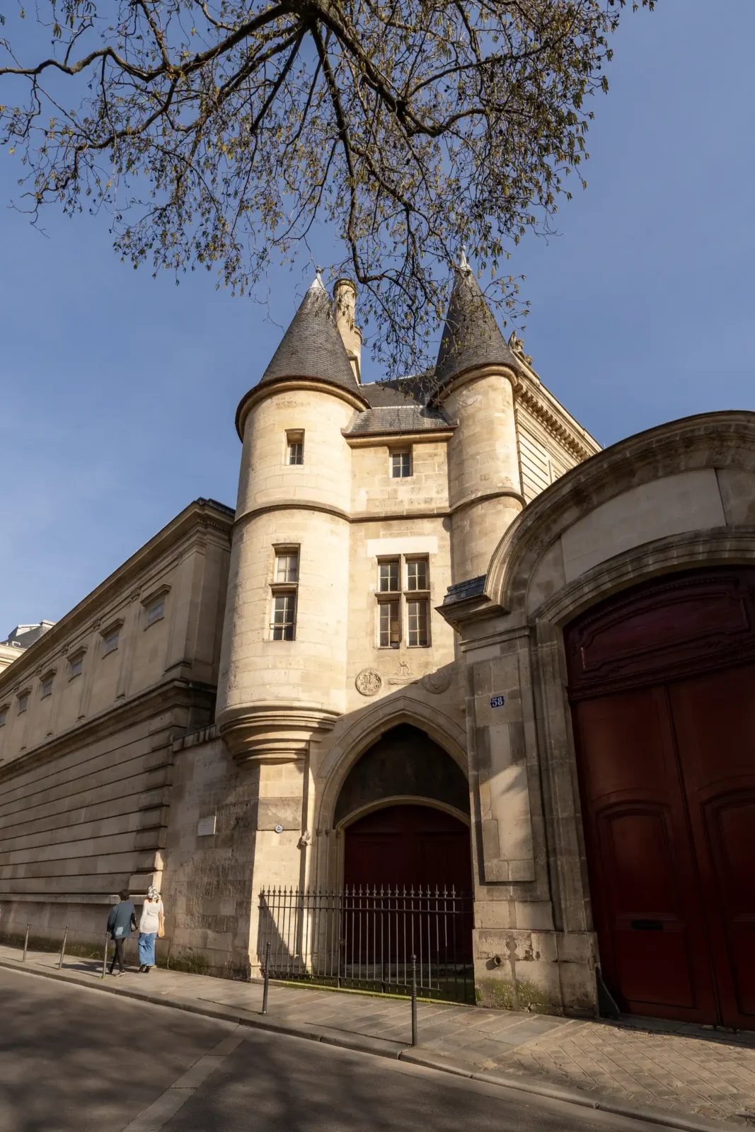 La façade en pierre des Archives nationales présente deux tourelles sous un ciel bleu.
