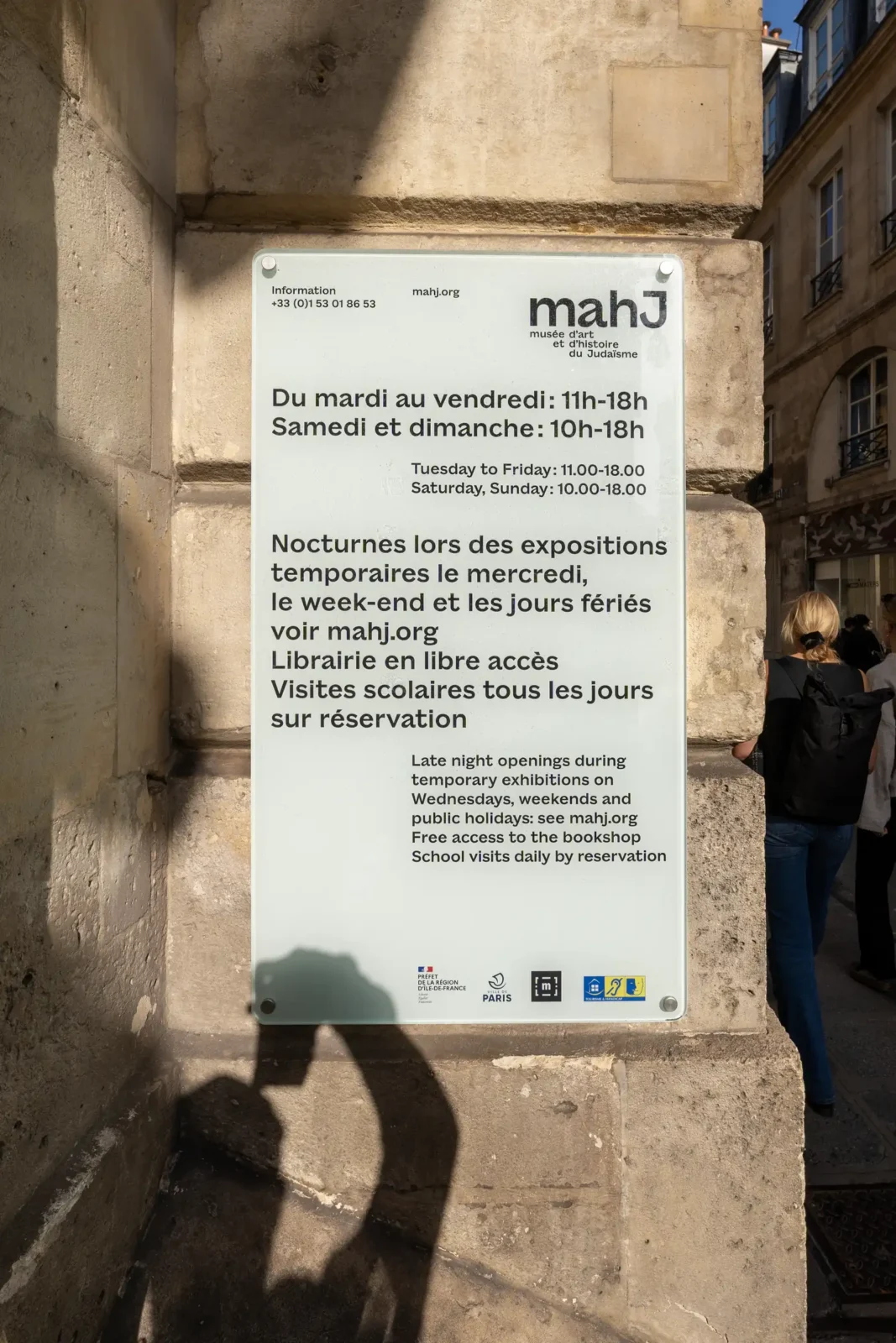 Panneau d'information en verre sur un mur en pierre du musée d'art et d'histoire.