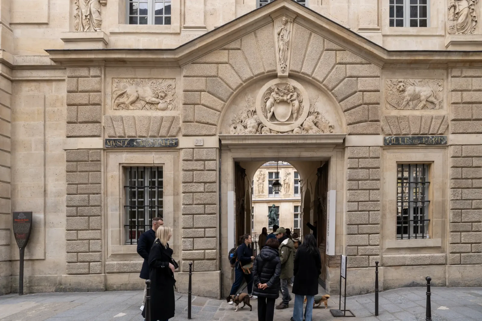 La façade sculptée du musée Carnavalet accueille des visiteurs devant son entrée principale historique.