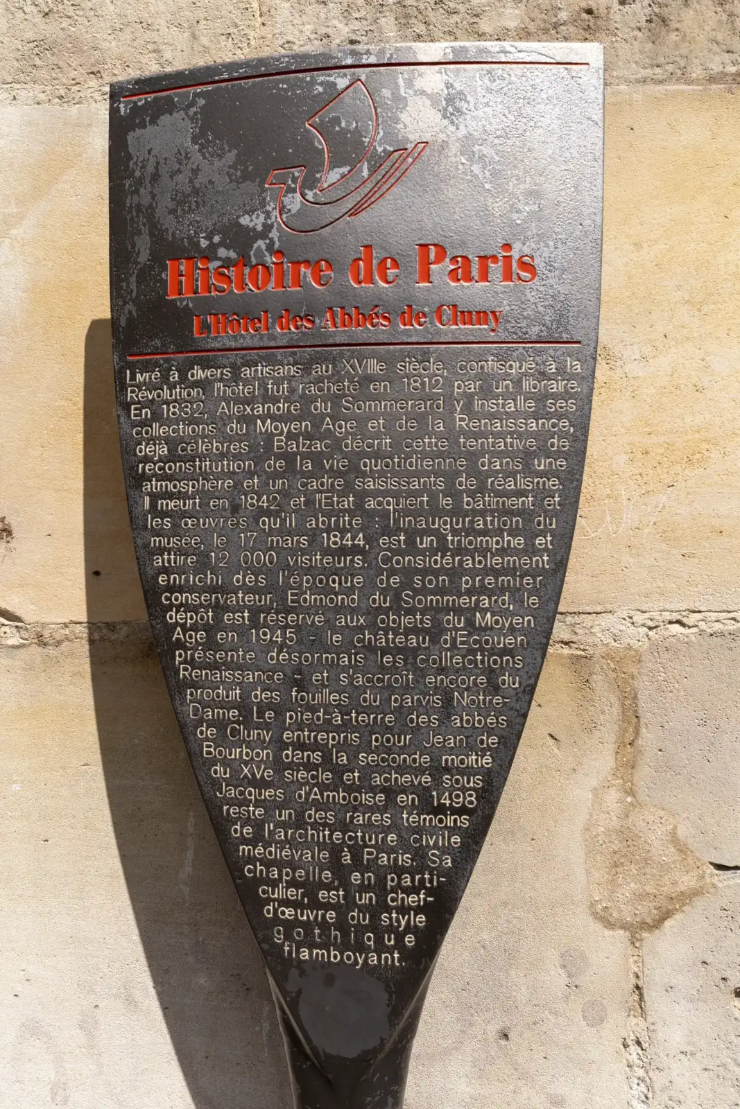 Panneau noir d'information Histoire de Paris fixé sur un mur en pierre ancienne.