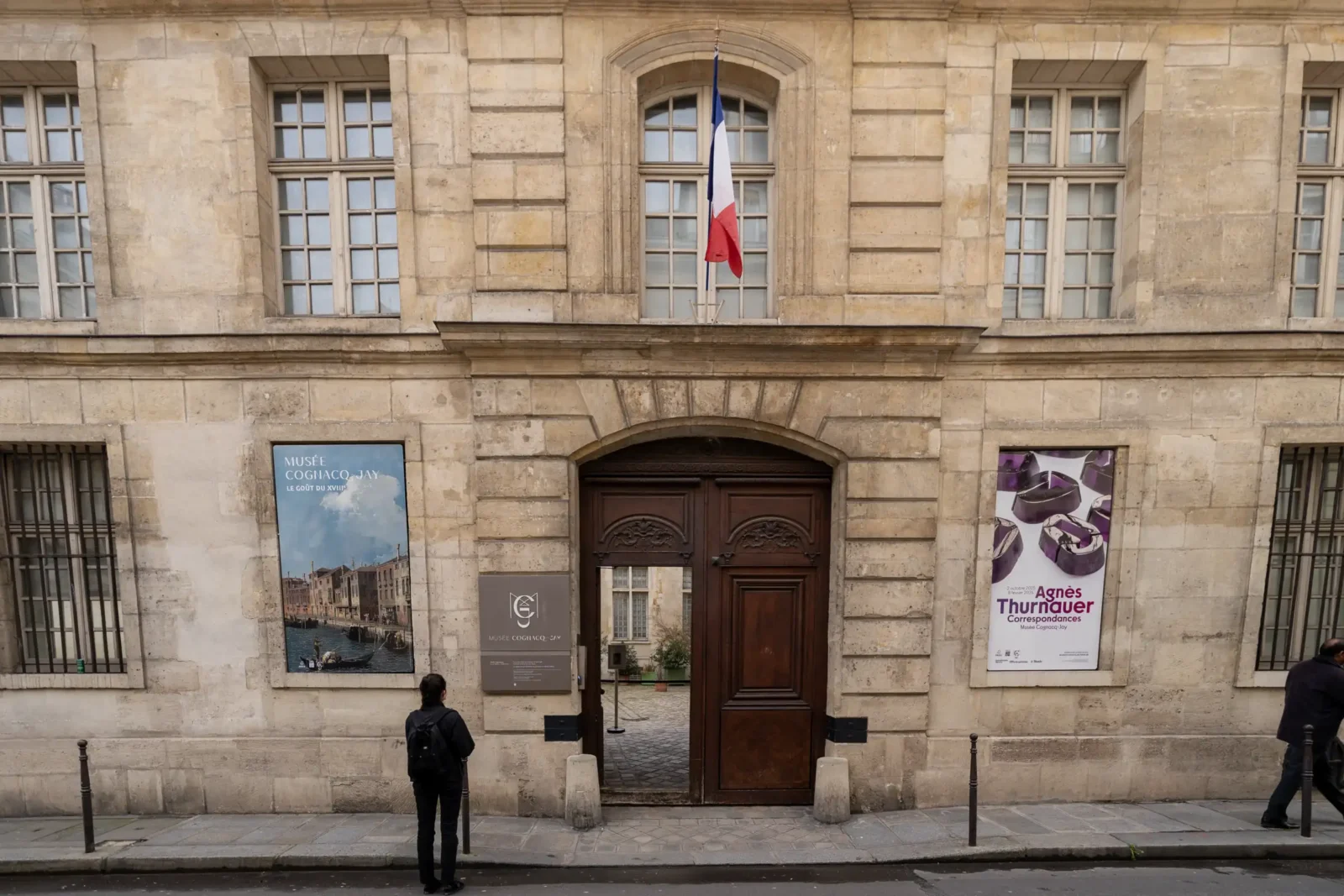La façade en pierre du musée Cognacq-Jay avec son entrée et ses affiches culturelles.