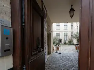 Vue sur la cour pavée du musée Cognacq-Jay à travers une porte en bois.