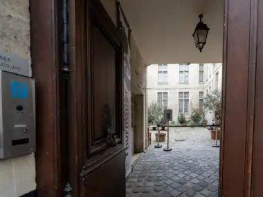Vue sur la cour pavée du musée Cognacq-Jay à travers une porte en bois.