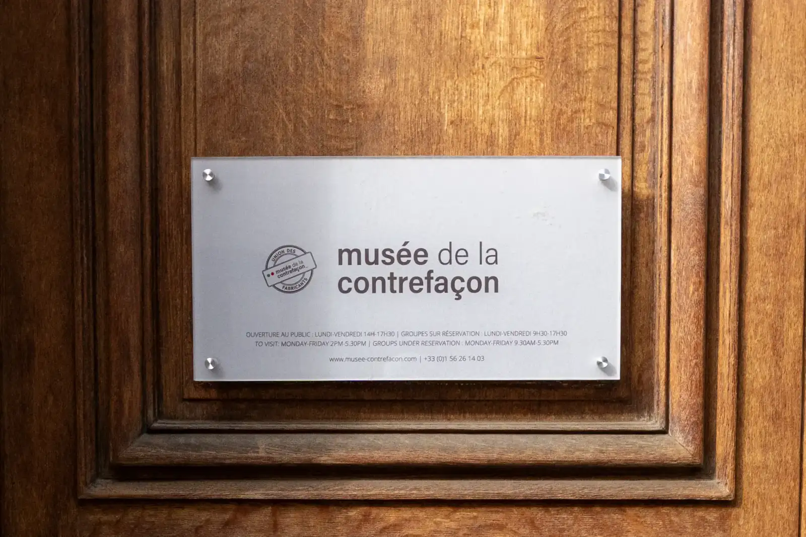 Une plaque en verre blanc et gris indiquant le musée de la contrefaçon.