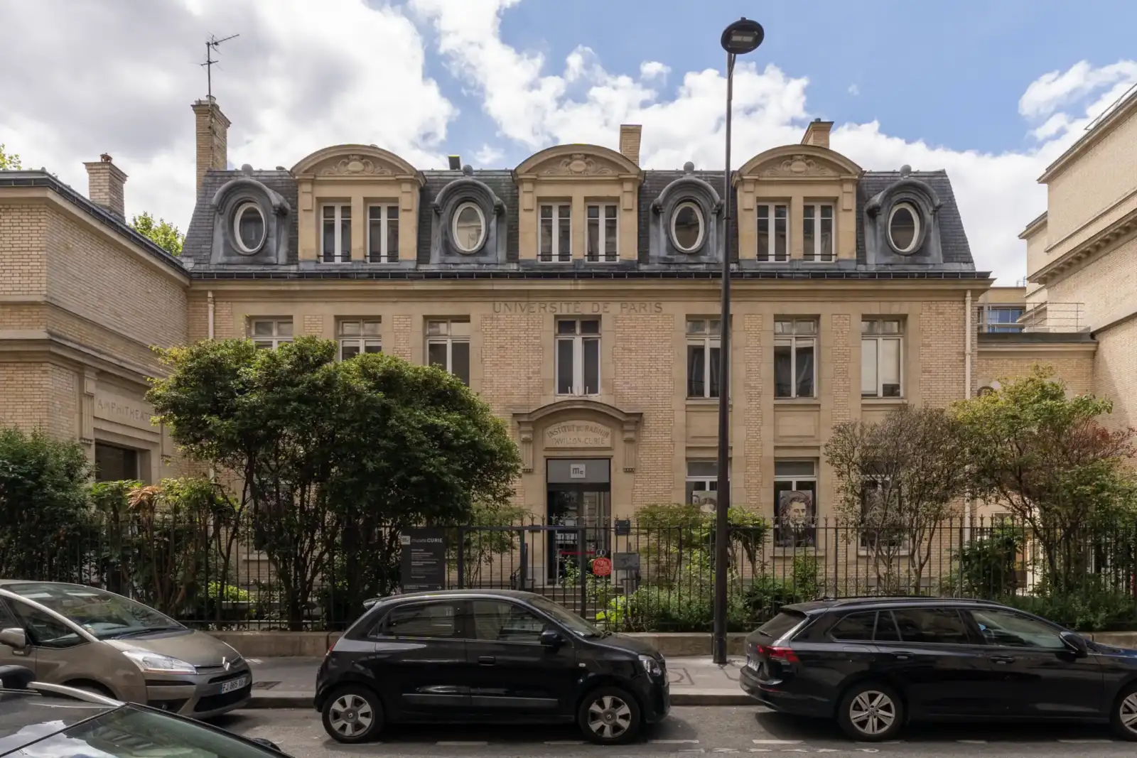 La façade classique du Musée Curie à Paris avec trois voitures garées devant.