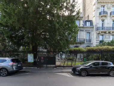 Façade classique du musée d'Ennery à Paris, en partie masquée par un grand conifère.