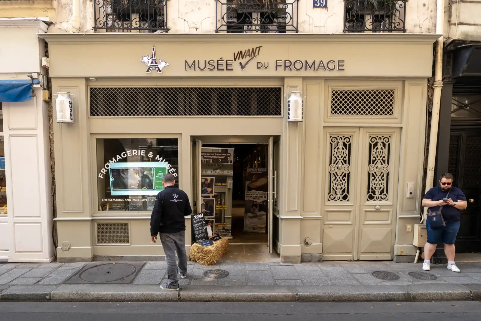 Façade beige du Musée Vivant du Fromage à Paris avec deux hommes debout devant.