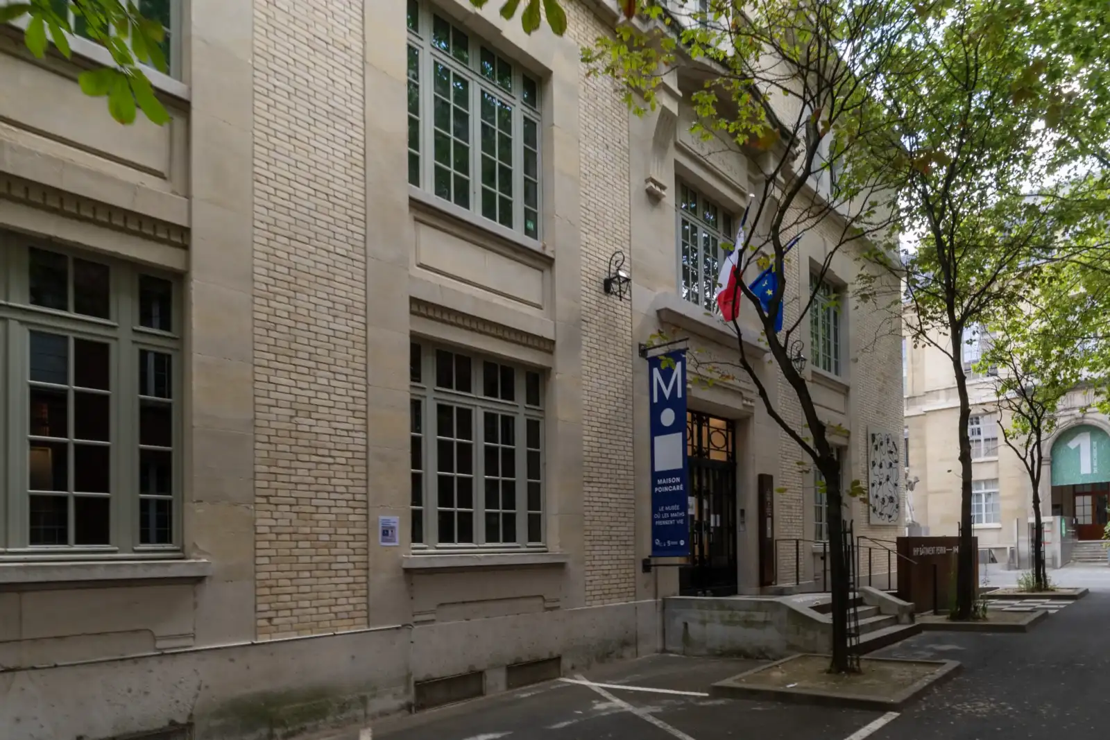 Vue de rue de la Maison Poincaré à Paris avec sa façade en briques claires.