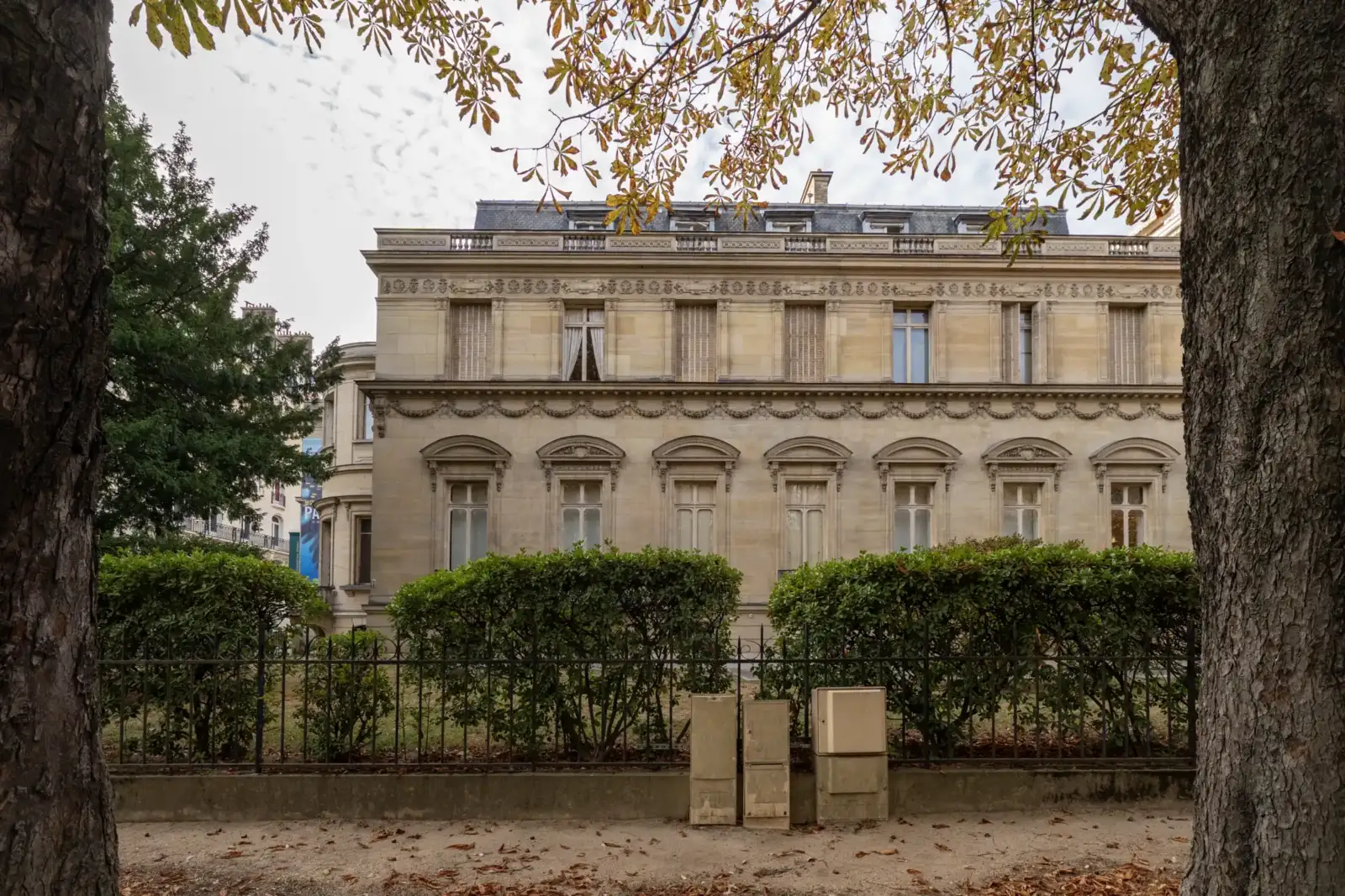 Façade en pierre claire du Musée Marmottan Monet encadrée par deux grands arbres.