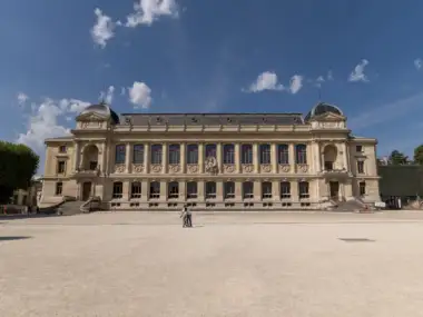 Vue de face de la grande galerie de l'Évolution sous un ciel bleu.