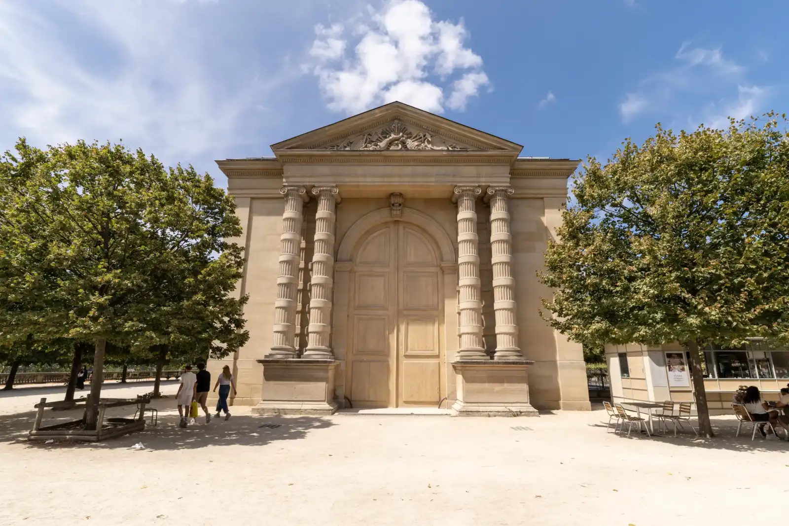 Façade classique du musée de lOrangerie à Paris encadrée par des arbres sous un ciel bleu.