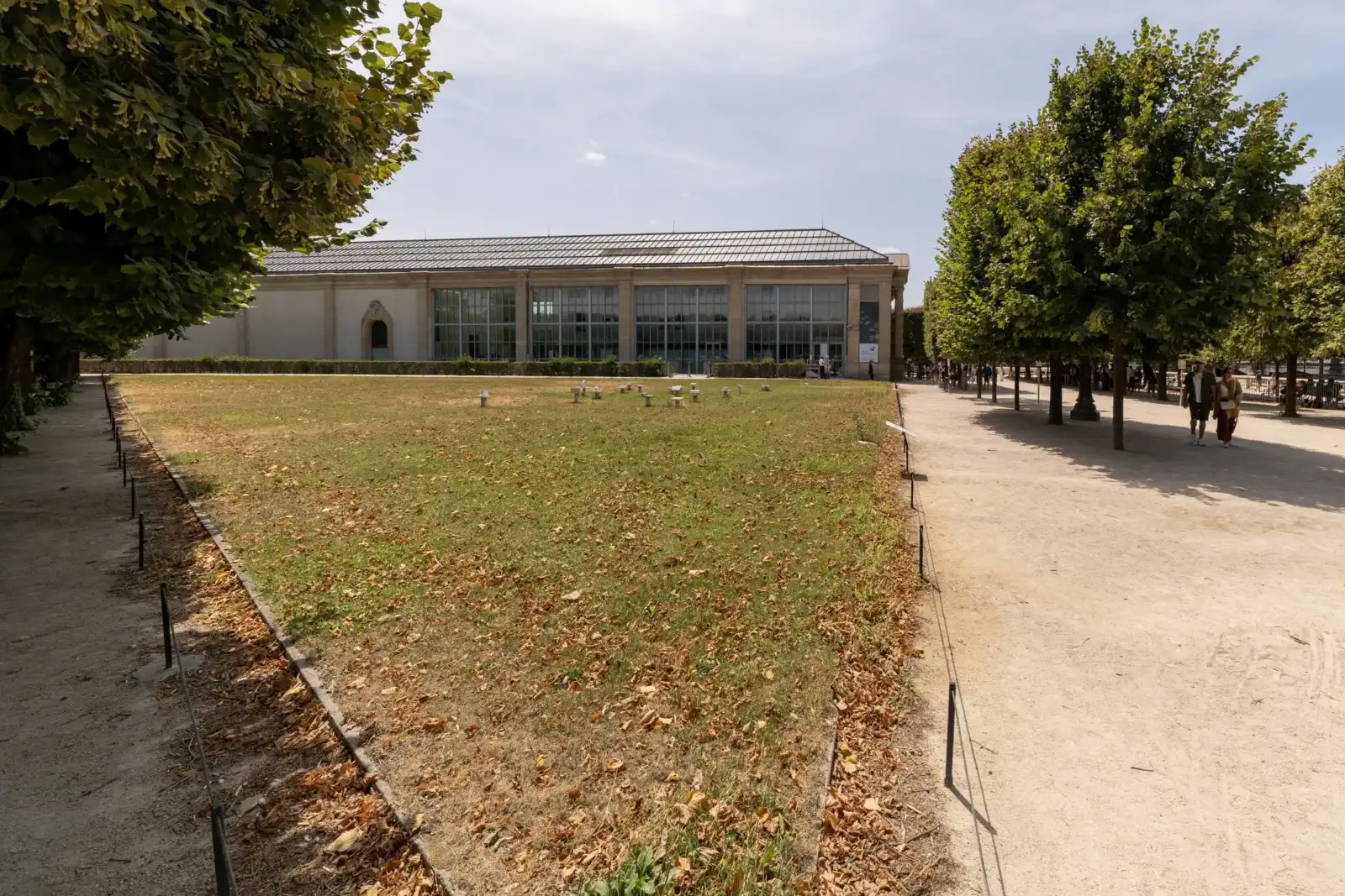 La longue façade vitrée du musée de l Orangerie derrière une pelouse arborée.