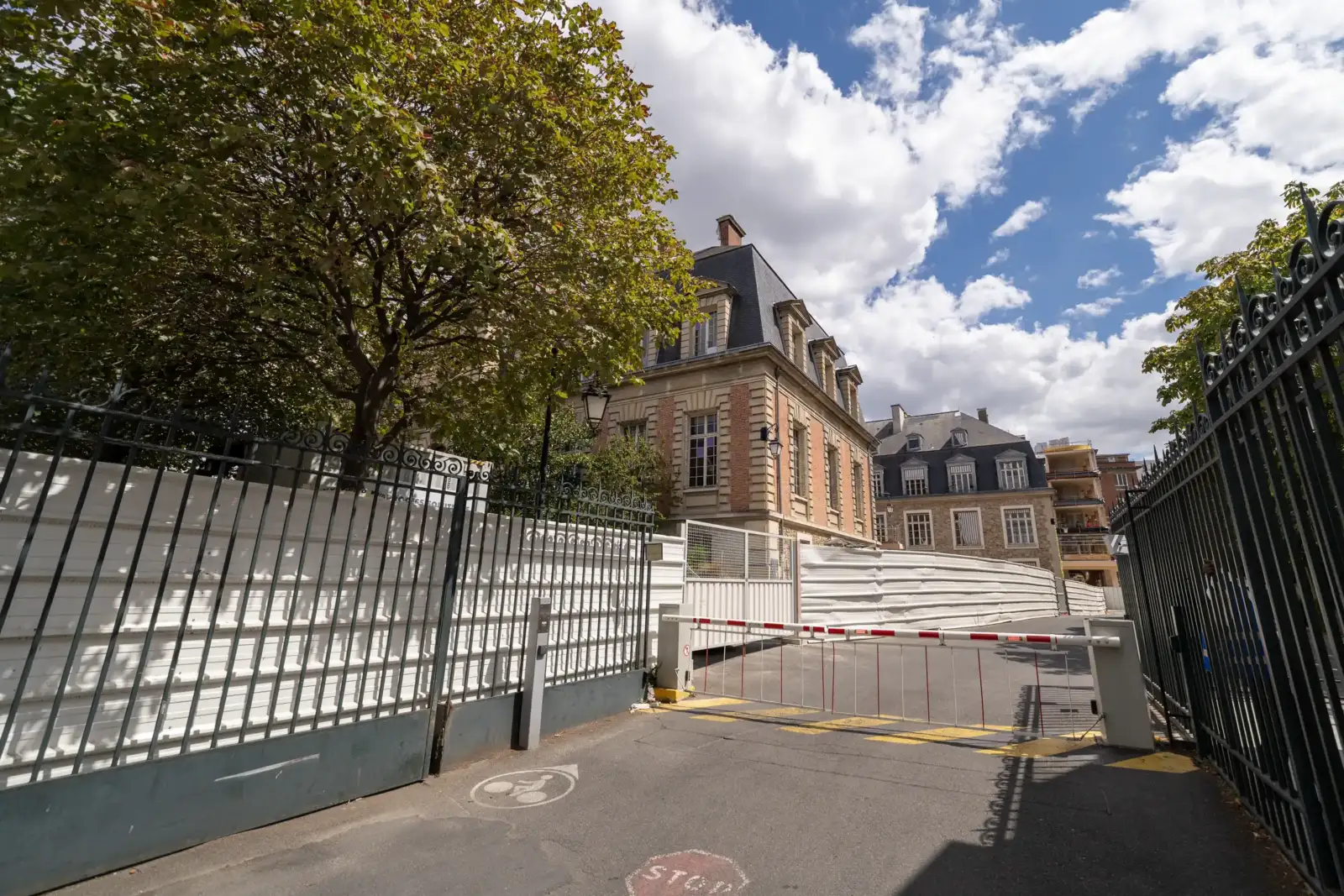 Vue de la façade du musée Pasteur à Paris derrière un portail métallique fermé.