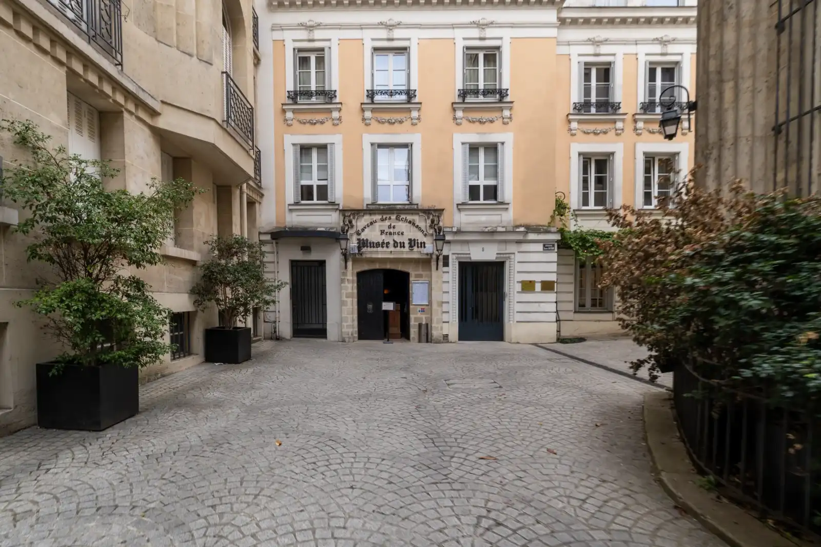 Vue de la façade principale du Musée du Vin de Paris, entourée de verdure.