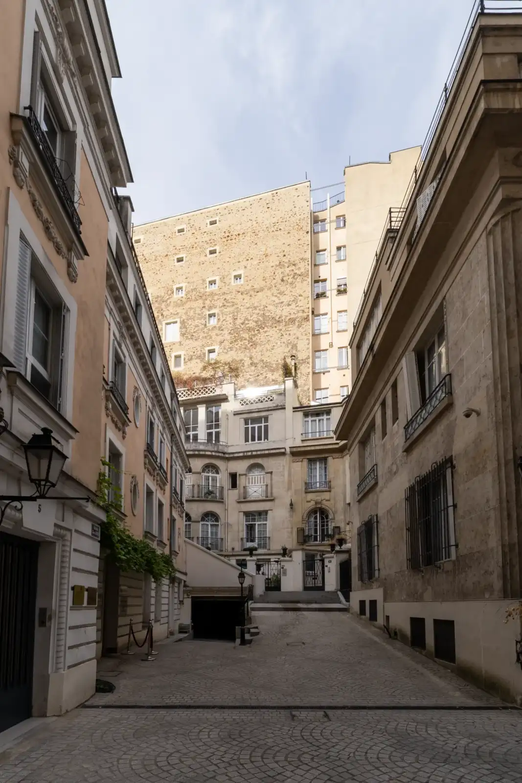 Rue pavée étroite entourée d'immeubles parisiens anciens en pierre de taille.
