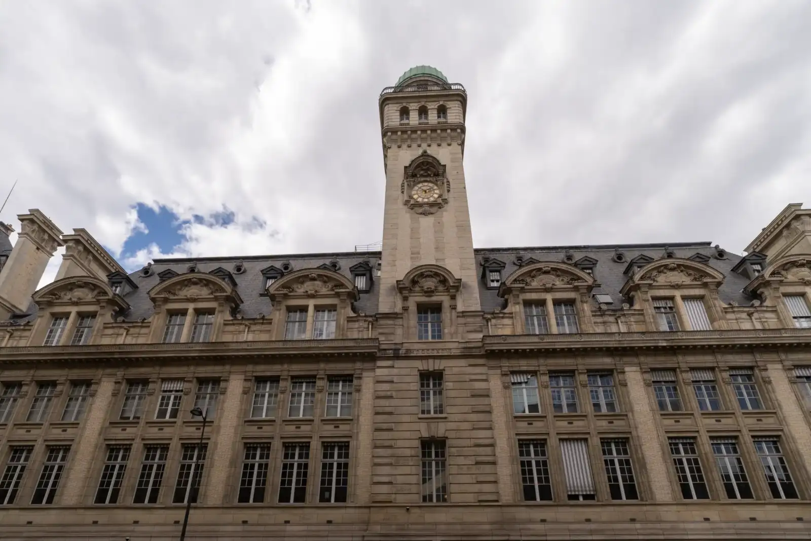 Façade de la Sorbonne sous un ciel nuageux avec sa tour munie d une horloge.