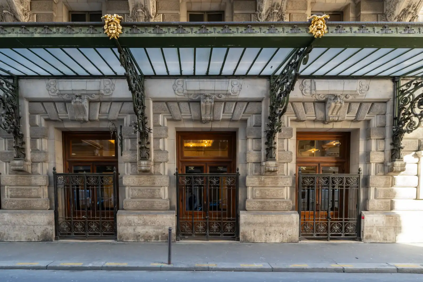 La façade en pierre de l'Opéra Comique présente trois portes sous une marquise ornée.