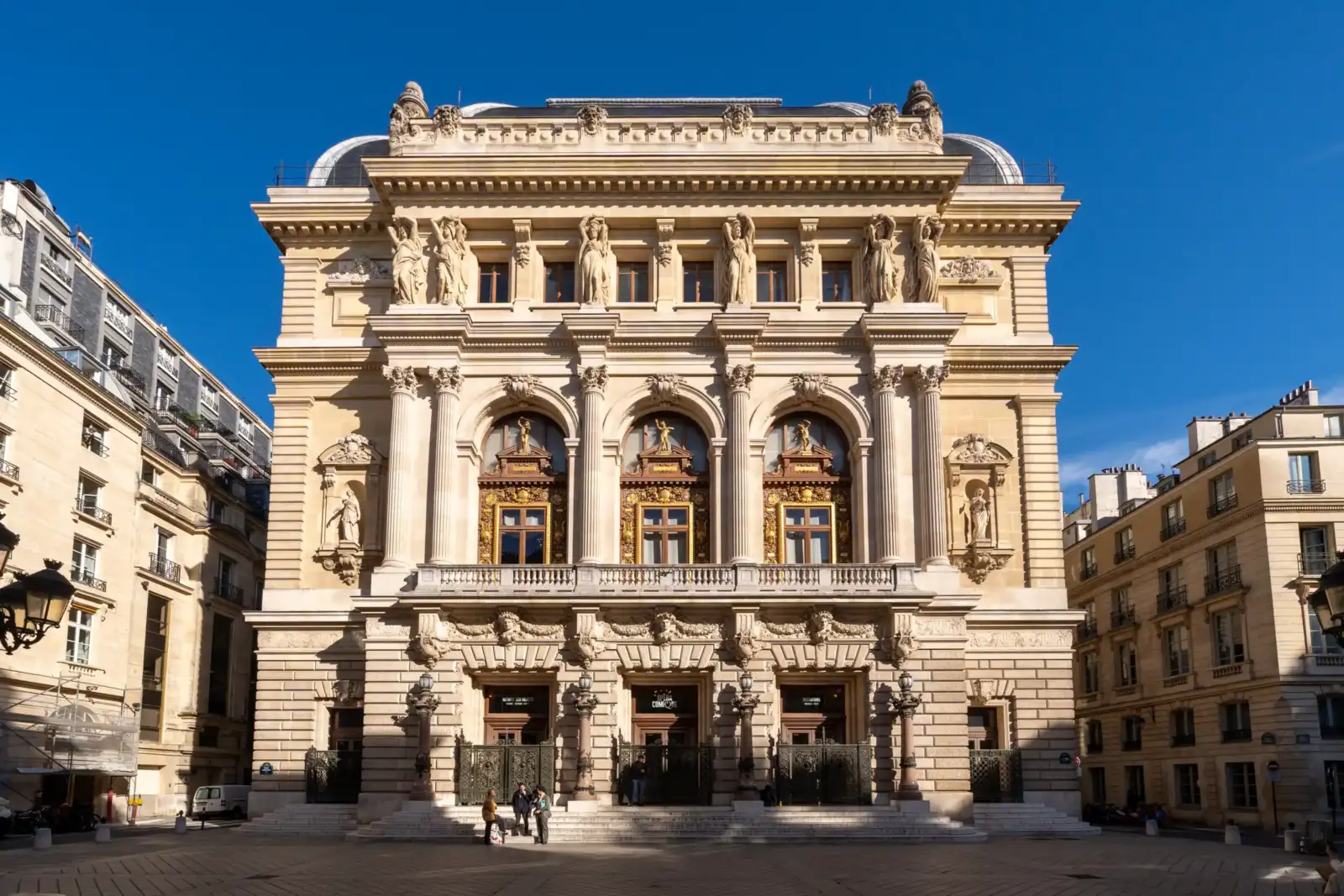 La façade monumentale de l'Opéra Comique à Paris sous un ciel bleu éclatant.