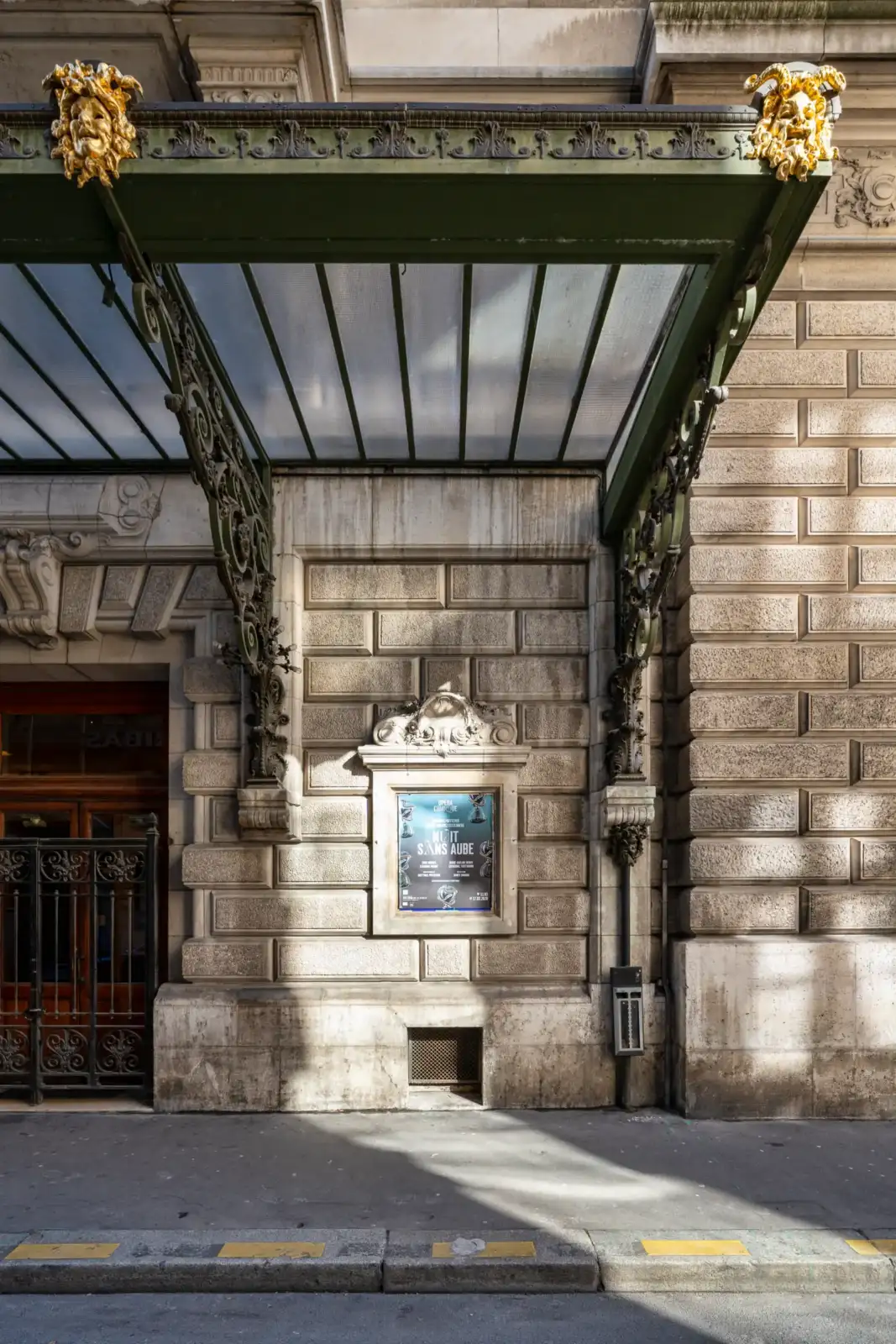 La marquise en fer forgé de l'Opéra Comique surplombe une affiche de spectacle murale.