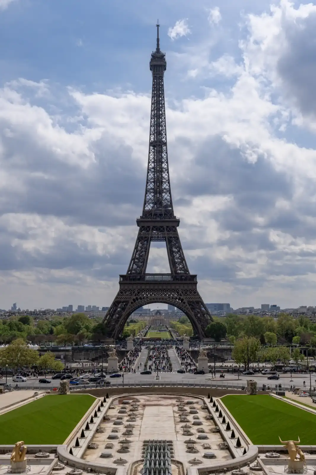 Vue plongeante depuis le Trocadéro sur la Tour Eiffel et Paris sous un ciel nuageux.