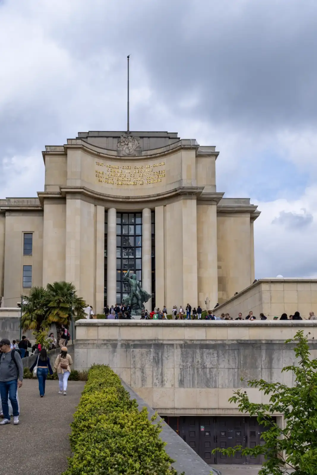 Vue de face du Palais de Chaillot à Paris, animé de nombreux touristes.