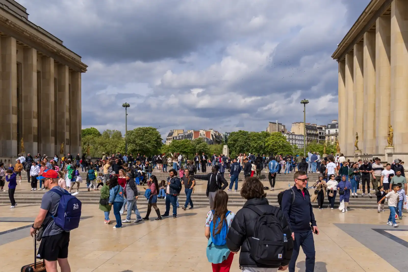Une foule animée se promène sur l esplanade du Trocadéro sous un ciel nuageux.