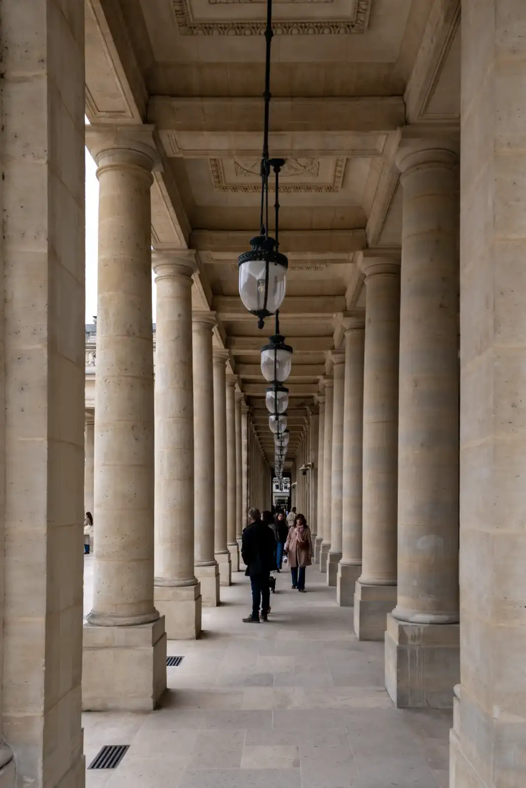 Des personnes marchent sous les colonnades historiques du Palais Royal à Paris en France.