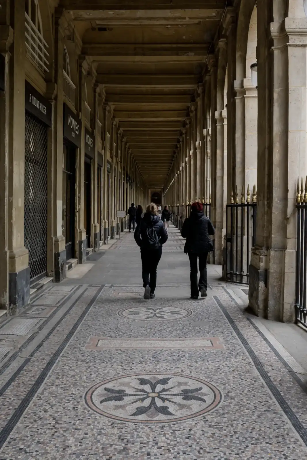 Deux personnes marchent sous les arcades historiques du Palais Royal à Paris en France.
