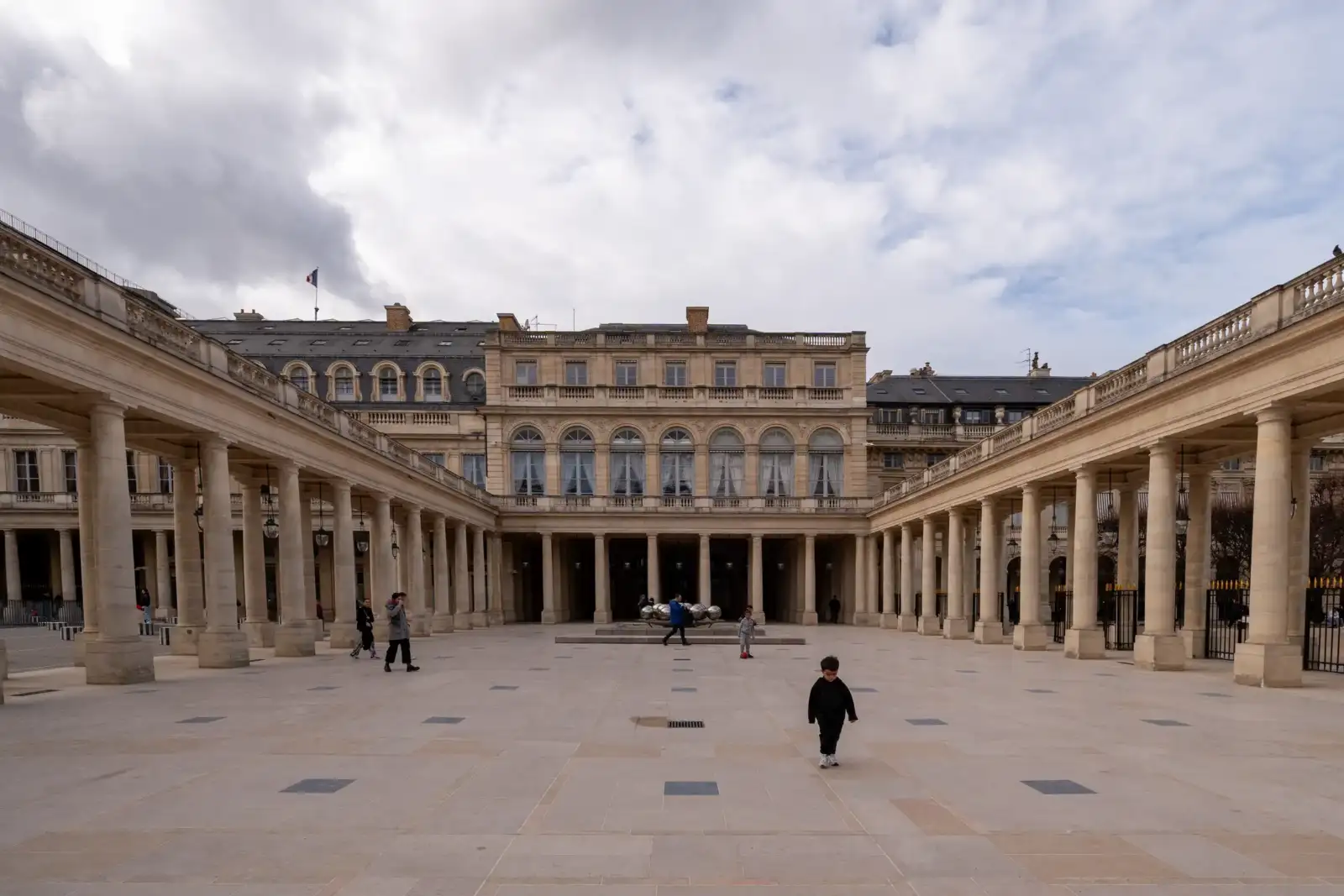 La façade classique du Palais Royal à Paris domine une cour pavée avec colonnades.