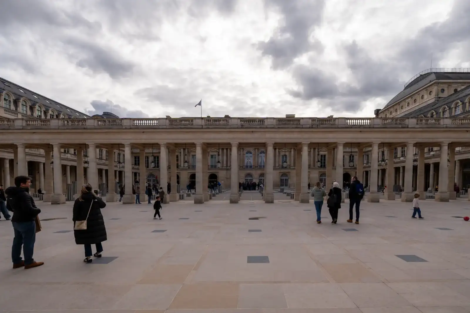 Des visiteurs se promènent dans la cour intérieure colonnade du Palais Royal à Paris.