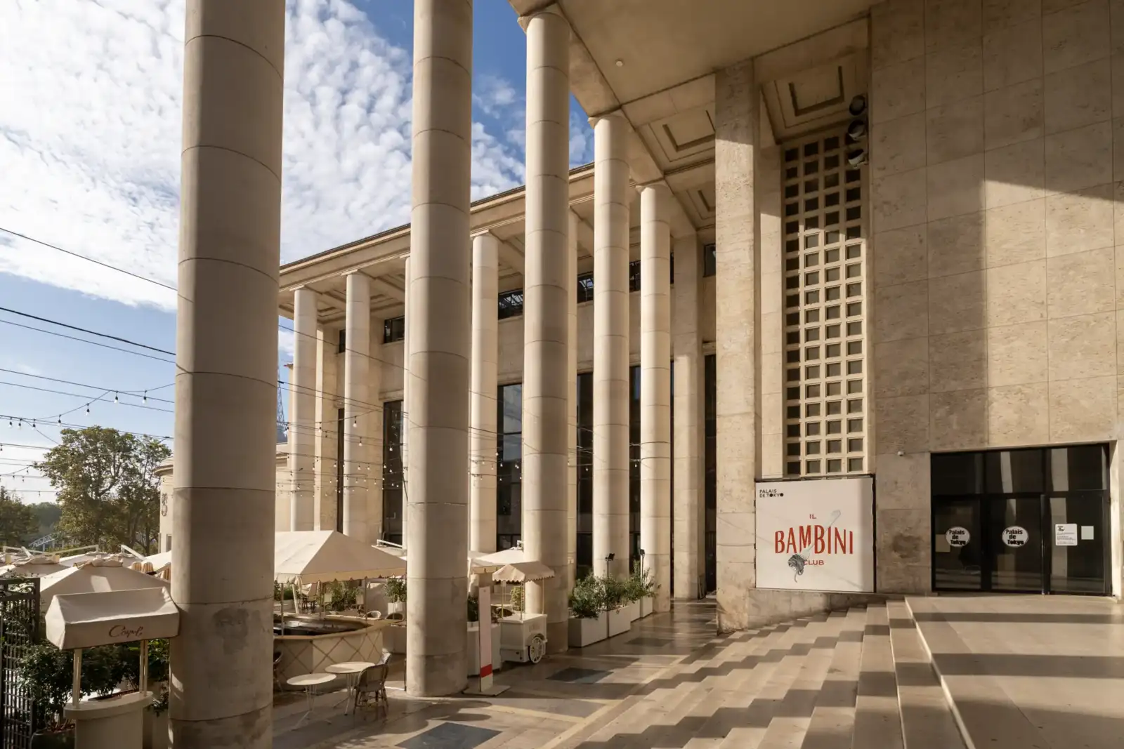 Imposantes colonnes de pierre du Palais de Tokyo sous un ciel bleu nuageux.