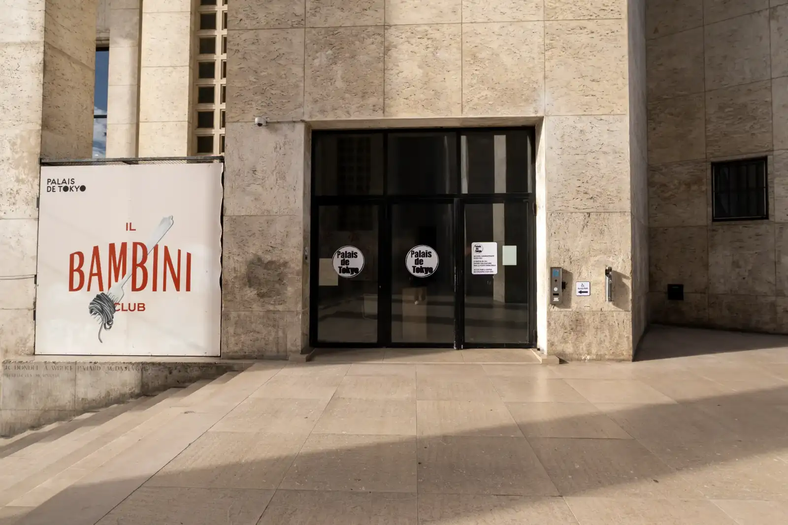 Façade en pierre beige du Palais de Tokyo avec signalétique et porte vitrée.