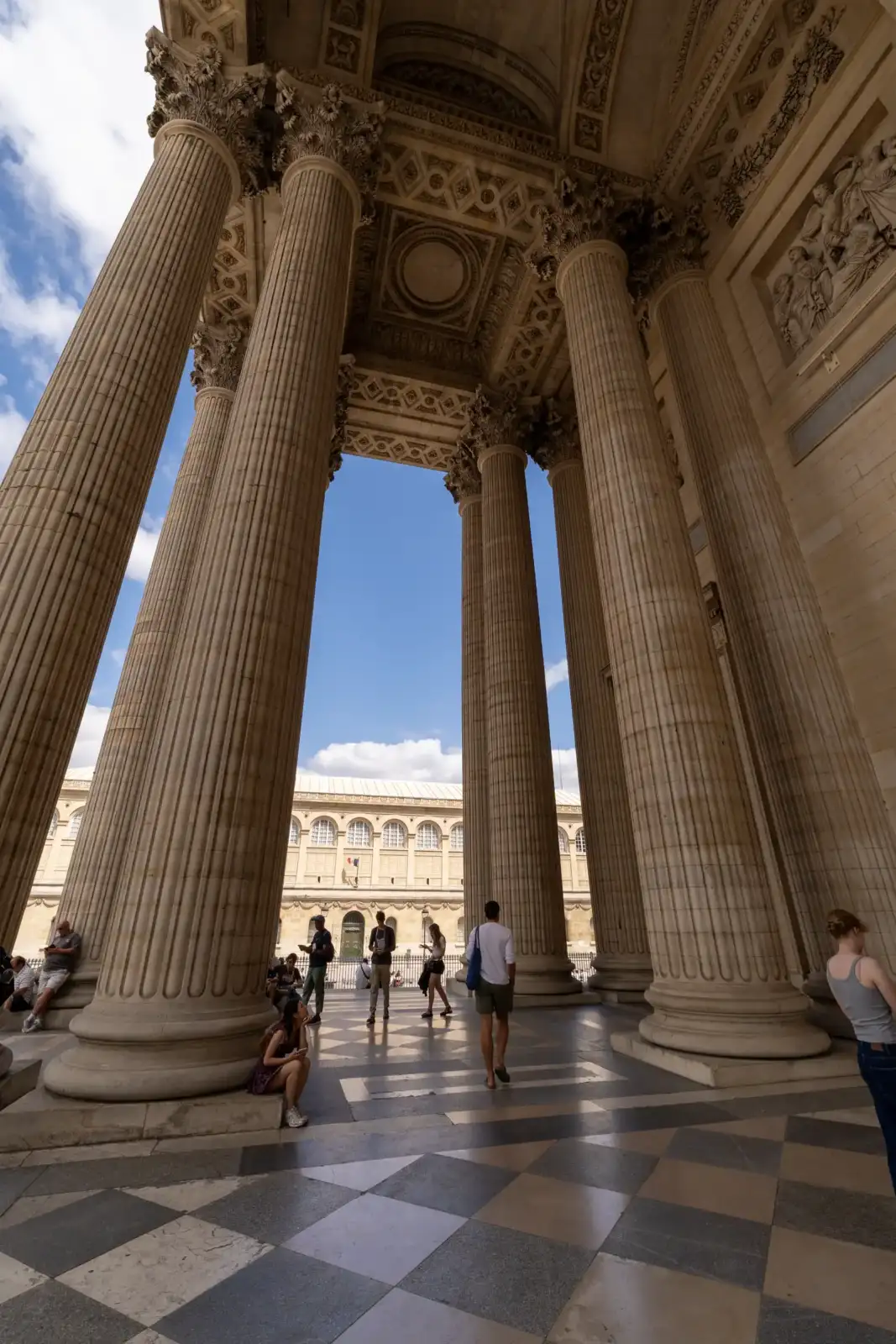 Vue en contre-plongée des grandes colonnes corinthiennes du Panthère à Paris sous un ciel bleu.