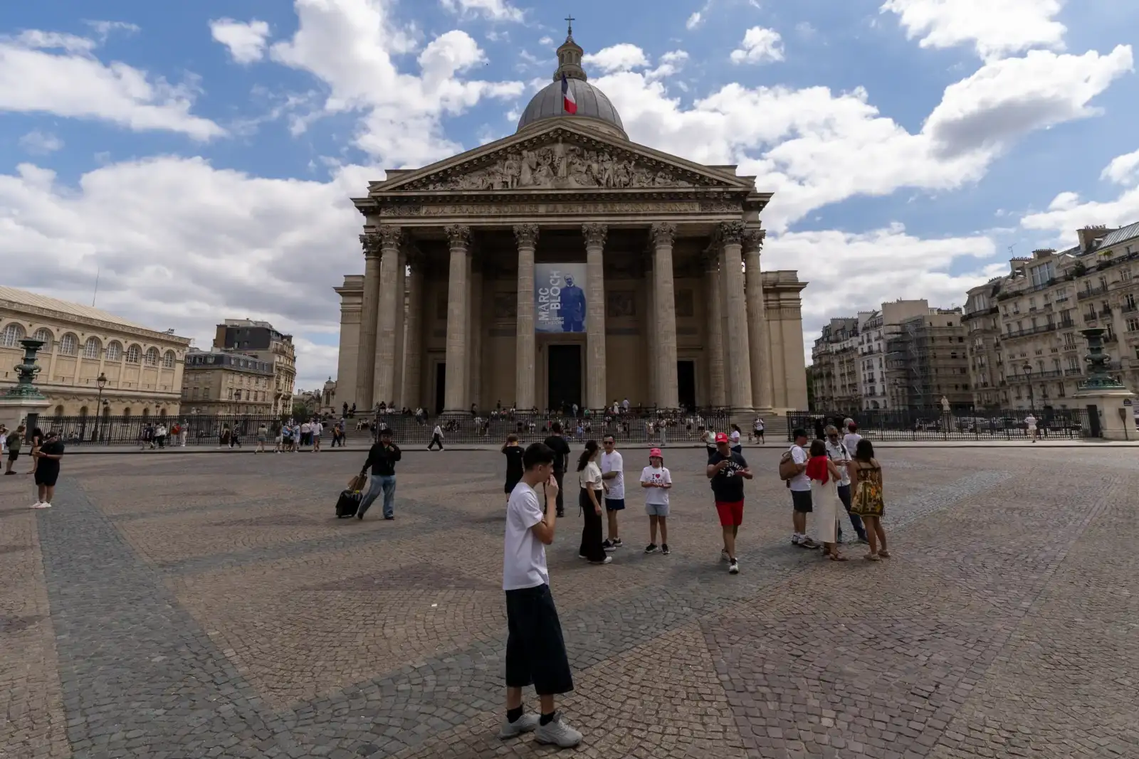 Vue de face du Panthéon de Paris avec sa coupole et des visiteurs au premier plan.