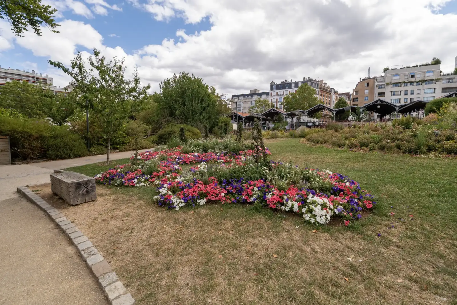 Un massif de fleurs colorées orne la pelouse du parc Georges Brassens à Paris.
