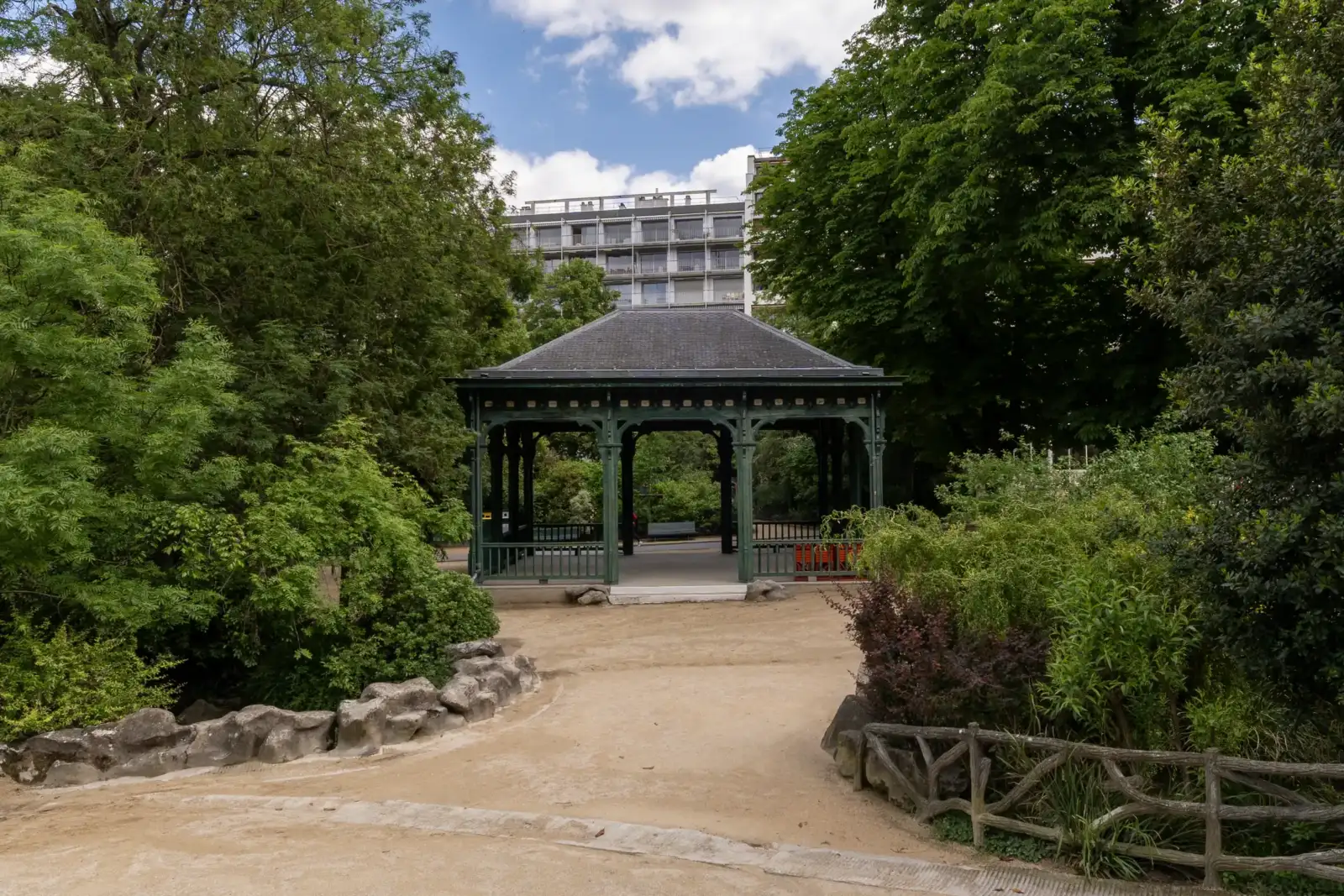 Un kiosque en bois vert se dresse au milieu des arbres au parc Montsouris.