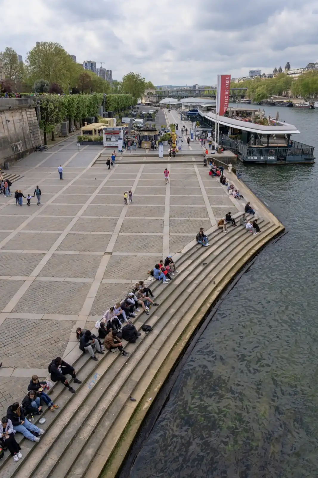 Des personnes se détendent sur les marches en pierre au bord de la Seine.
