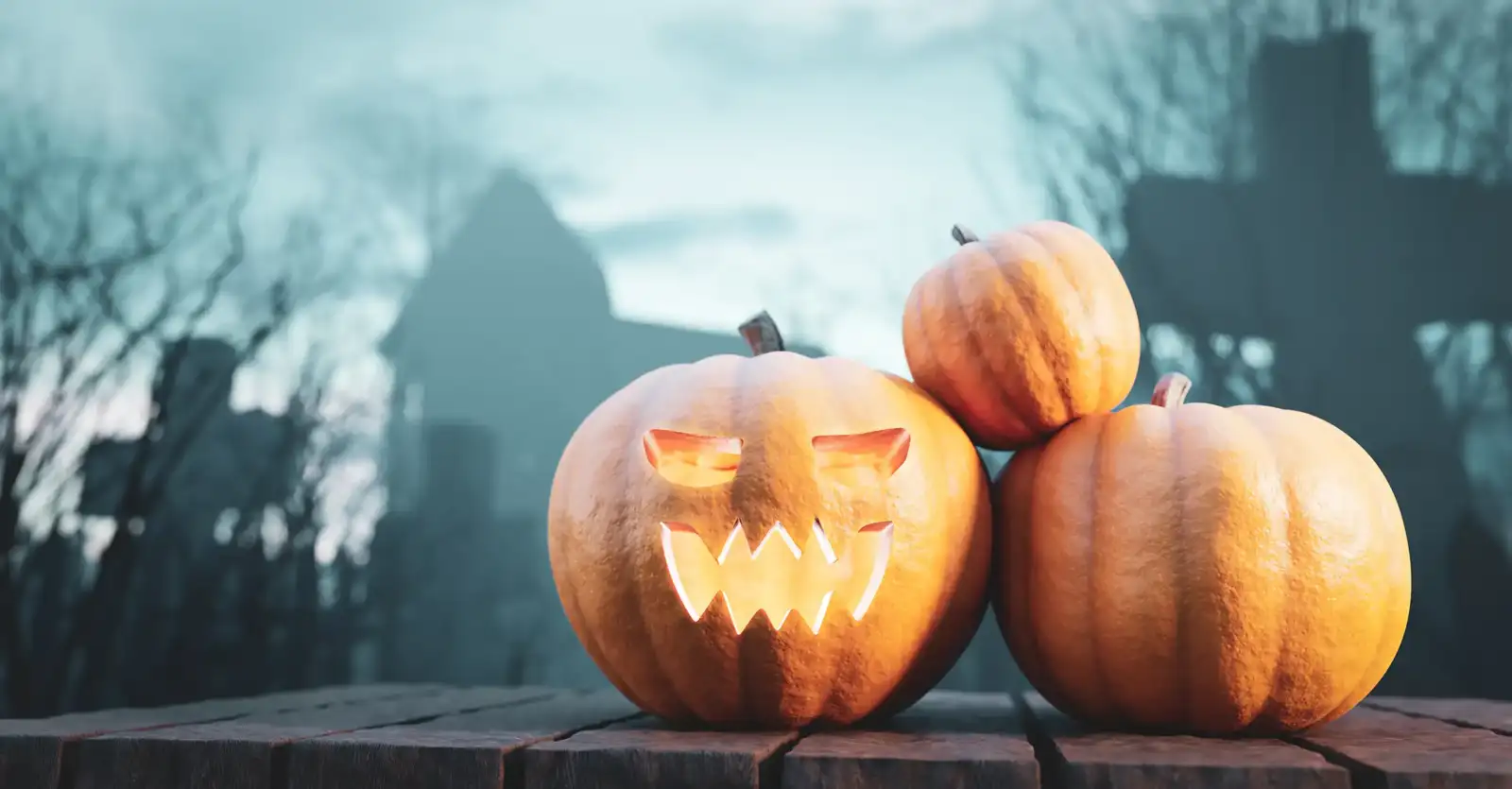 Trois citrouilles d Halloween illuminées reposent sur une table en bois en extérieur.