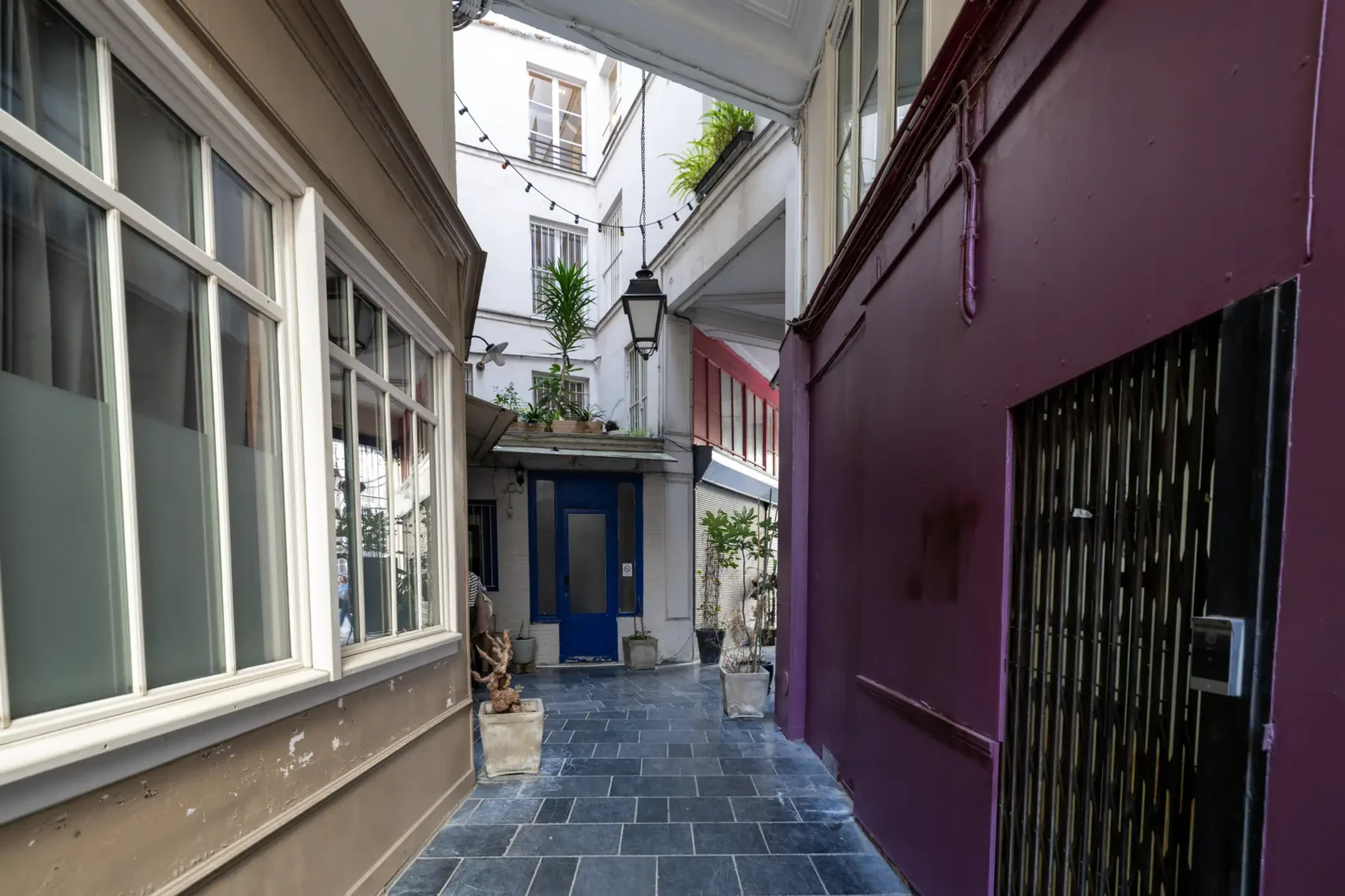 Une ruelle pavée étroite à Paris avec des murs colorés et des plantes vertes.