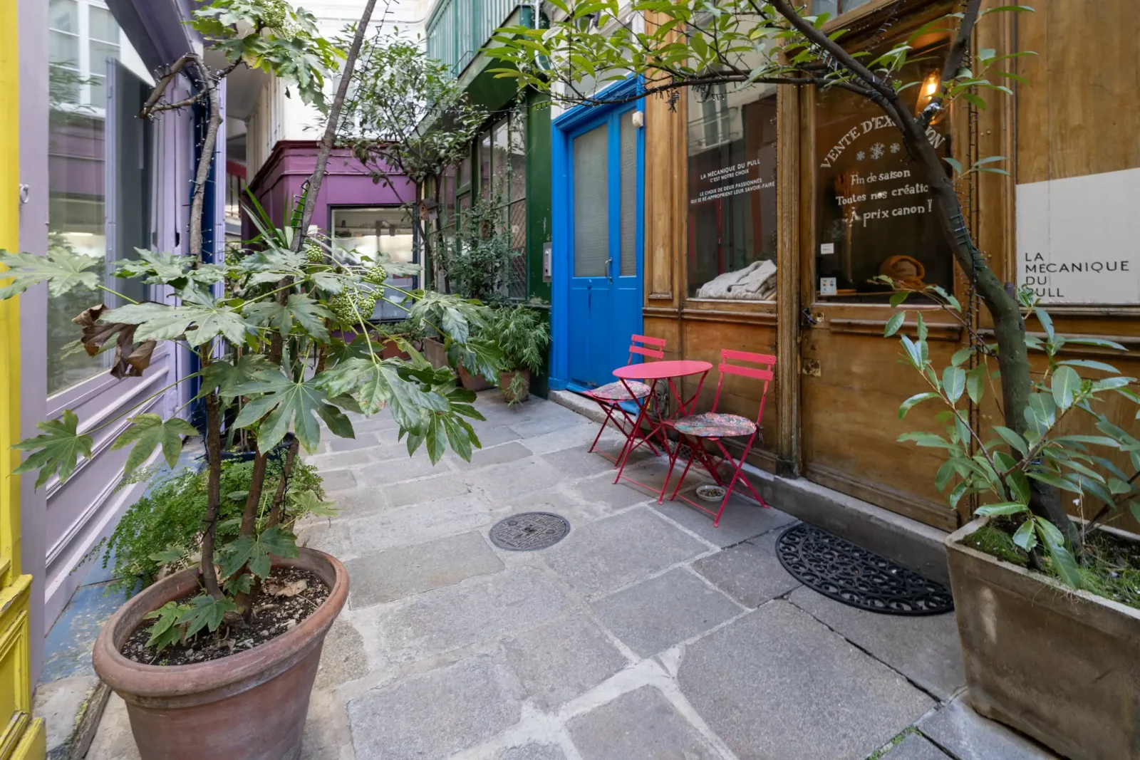 Une petite table et deux chaises roses décorent ce passage parisien fleuri et coloré.