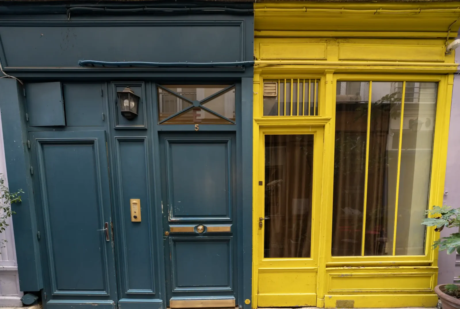 Une porte bleue et une vitrine jaune contrastent sur une façade du passage Ancre.