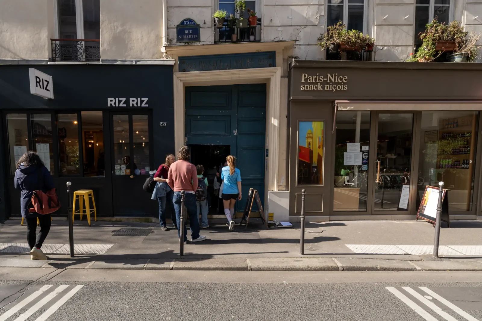 Des personnes entrent dans le Passage de l'Ancre situé entre deux commerces parisiens.
